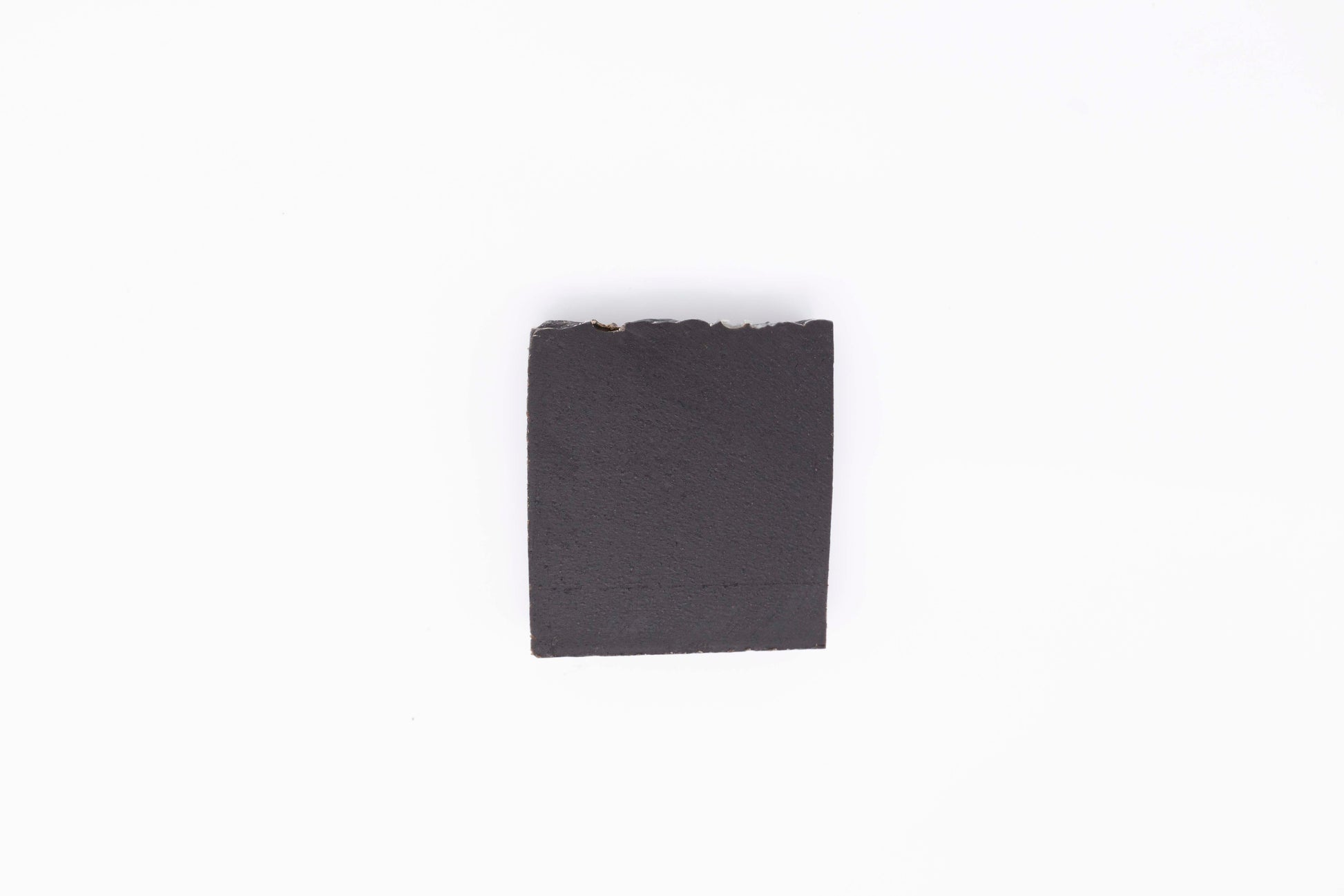 A charcoal black Midnight Anise soap bar sits on a clean white backdrop
