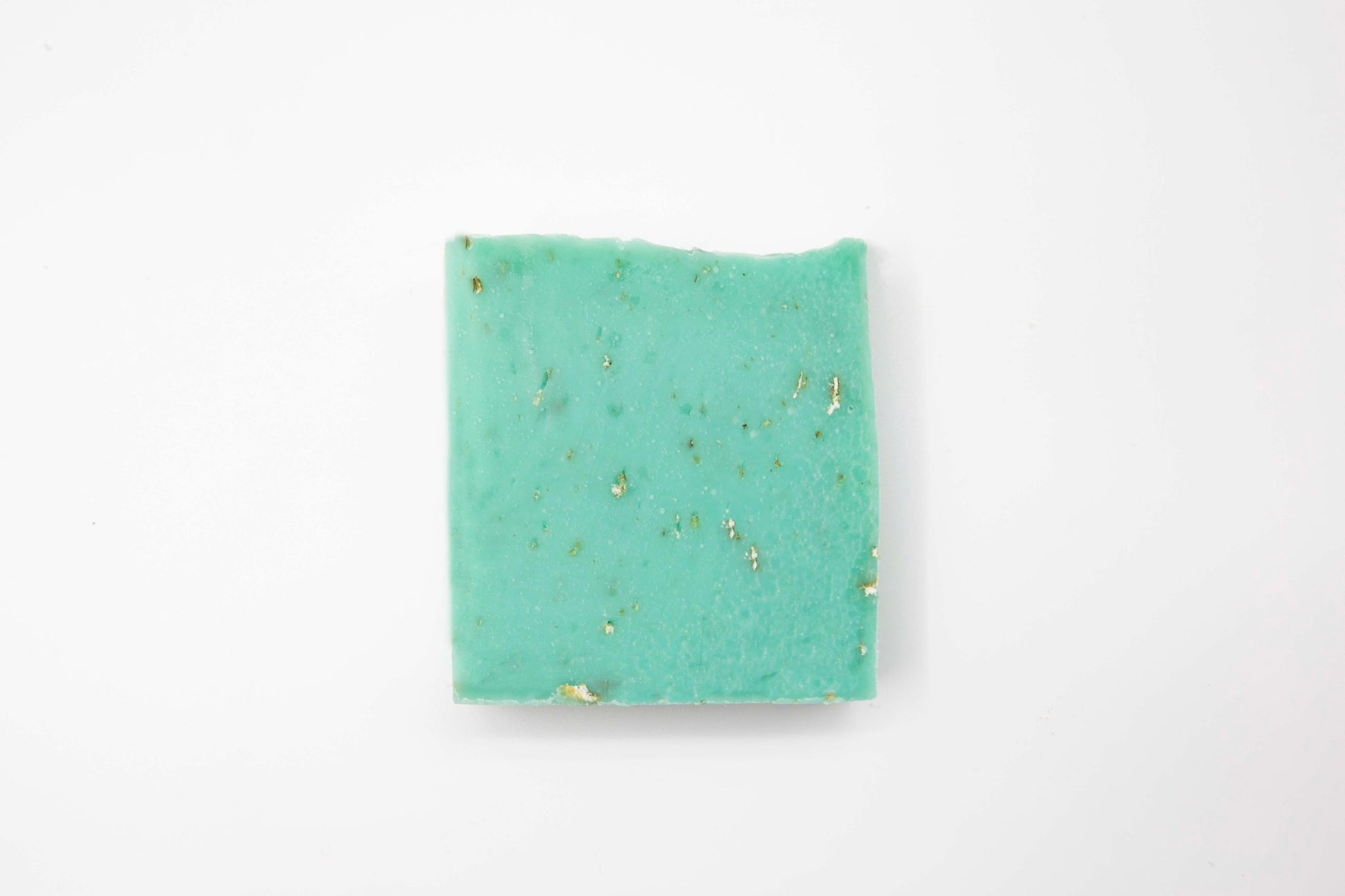 Aqua blue eucalyptus oatmeal soap bar flecked with ivory colored oats sits on a clean white background.