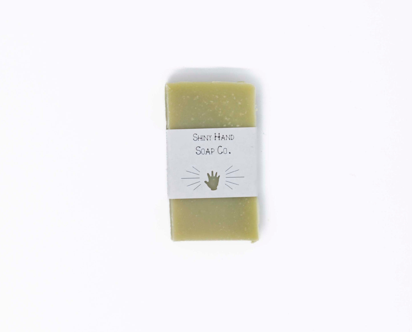 One bright fresh vibrant green bergamot pine miniature soap bar sits on a clean white background with a white paper wrapper that has a hand shape cut out of it.
