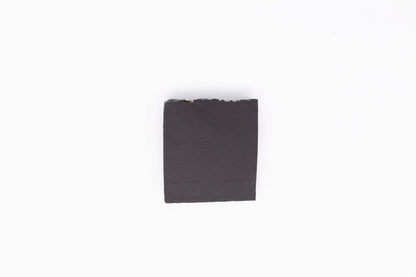 A charcoal black Midnight Anise soap bar sits on a clean white backdrop