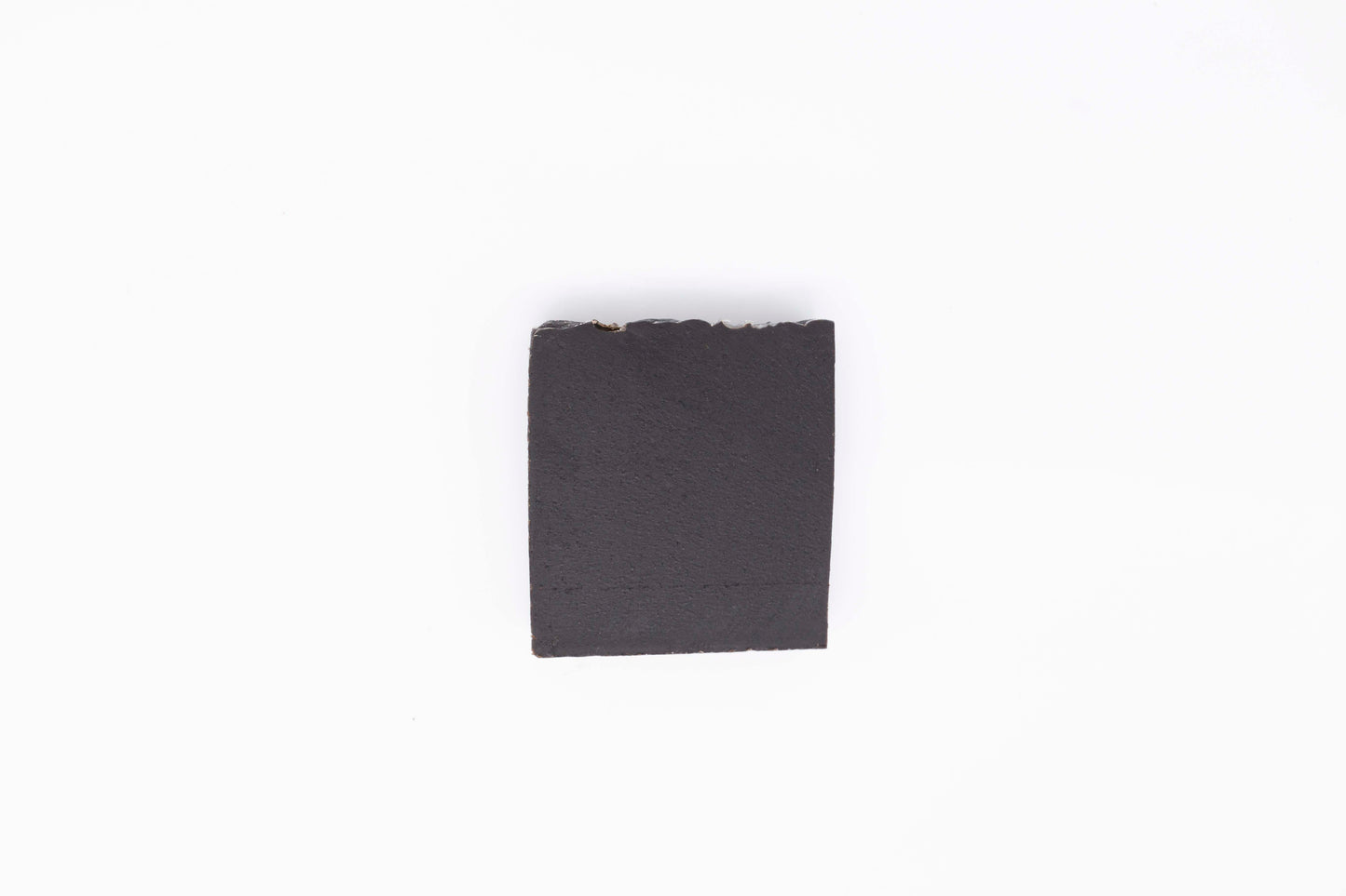 A charcoal black Midnight Anise soap bar sits on a clean white backdrop