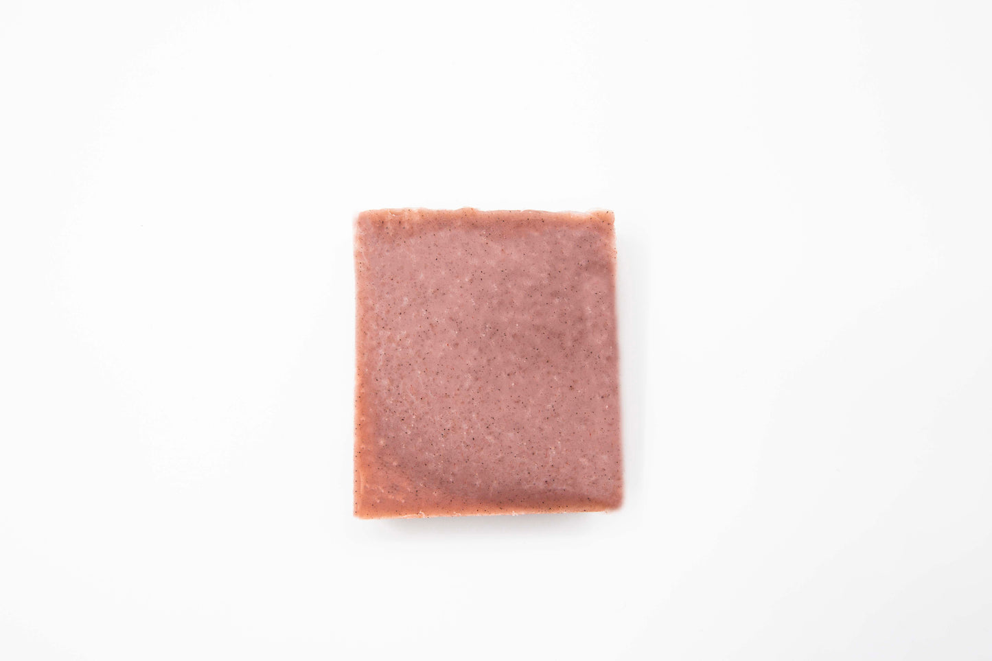 Pale red Cinnamon rosemary soap bar speckled with dark brown cinnamon sits on a clean white background